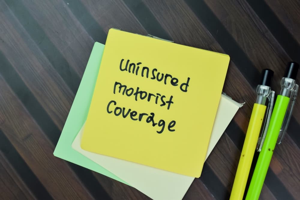 Concept of Uninsured Motorist Coverage write on sticky notes isolated on Wooden Table.